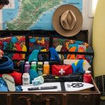 surfer packing surfboard travel bag for surf trip