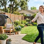 A homeowner cleanly mounting a retractable garden hose reel on an exterior wall.