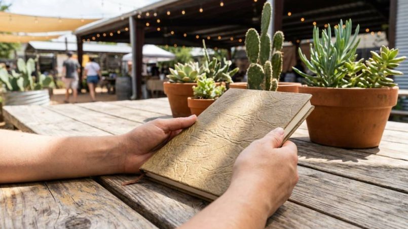 Artisan displaying handcrafted plant-based western boots in sunny Austin workshop.